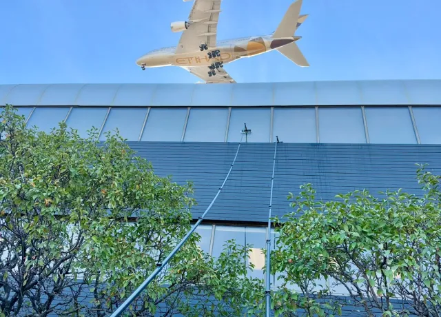 SKYPOLE water-fed poles cleaning exterior windows at Panasonic Canada in Mississauga as an Etihad aircraft passes overhead.