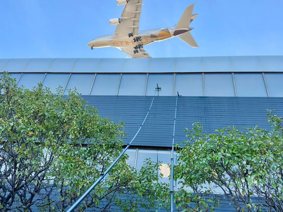 SKYPOLE water-fed poles cleaning exterior windows at Panasonic Canada in Mississauga as an Etihad aircraft passes overhead.
