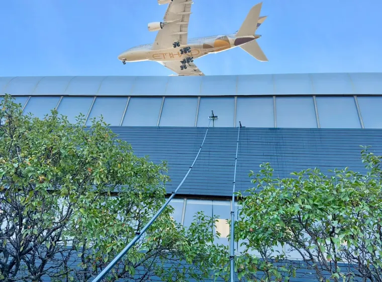 SKYPOLE water-fed poles cleaning exterior windows at Panasonic Canada in Mississauga as an Etihad aircraft passes overhead.