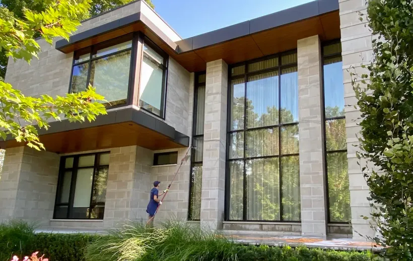 Modern house with large windows and person cleaning.