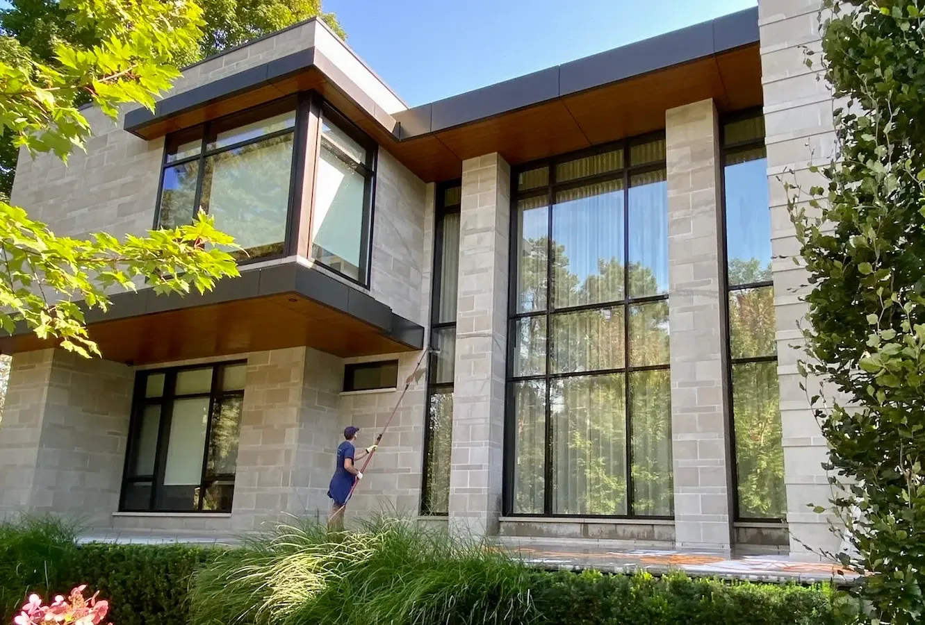 Modern house with large windows and person cleaning.