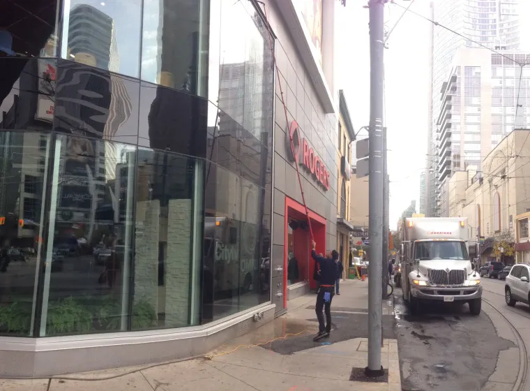 Rogers store on urban street with pedestrians and reflective windows.