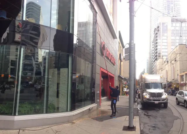 Rogers store on urban street with pedestrians and reflective windows.