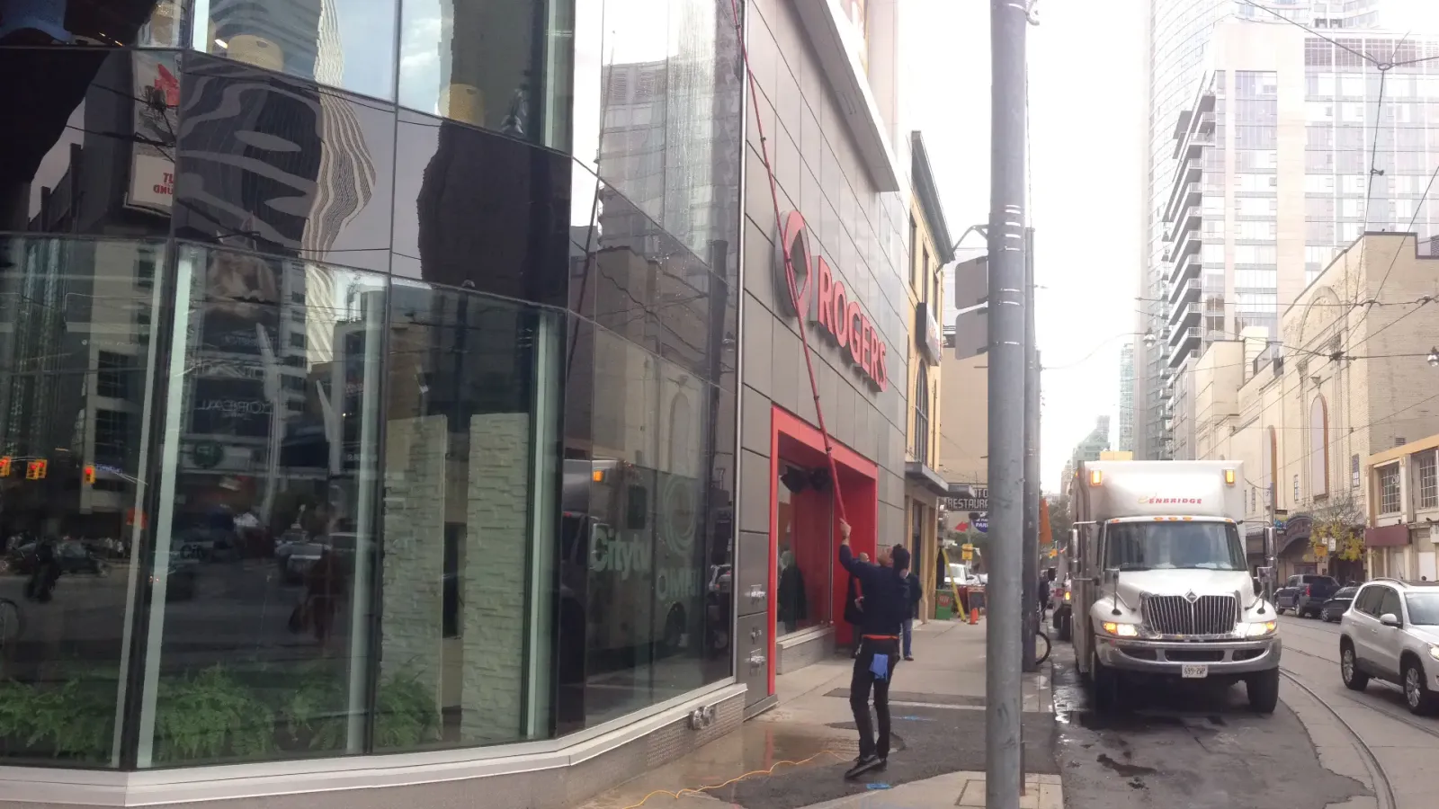 Rogers store on urban street with pedestrians and reflective windows.