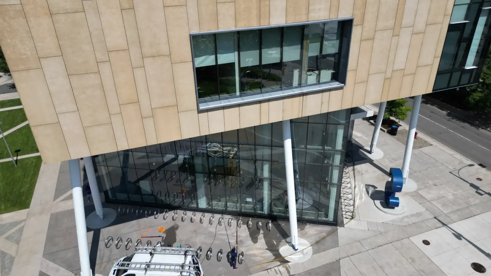 Aerial view of modern building with glass facade and parked van.