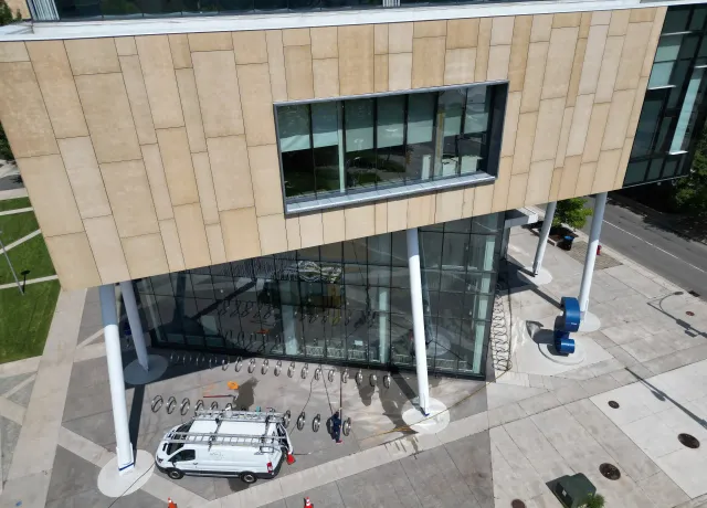Aerial view of modern building with glass facade and parked van.