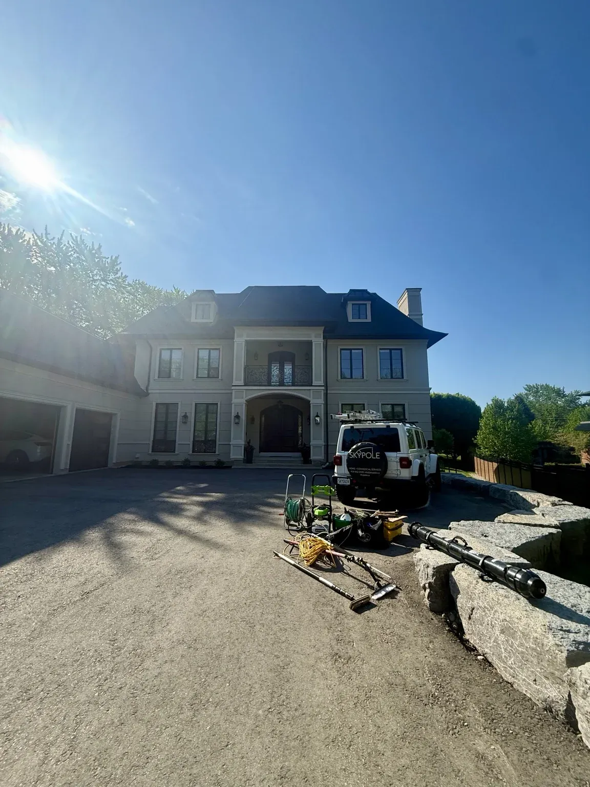 SKYPOLE window cleaning equipment and service vehicle positioned outside a luxury home before exterior cleaning.