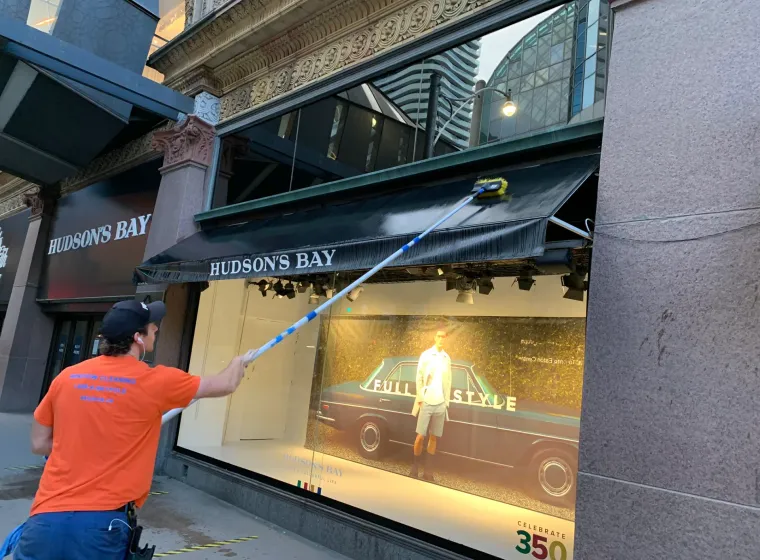 Worker cleaning Hudson's Bay store window display.