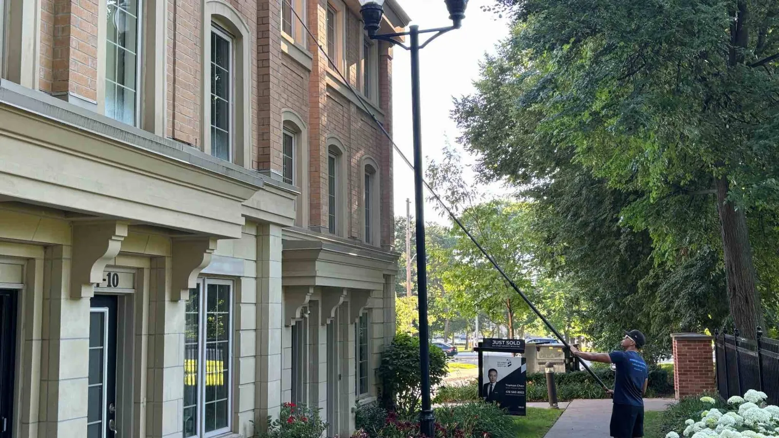 Man cleaning windows at elegant townhouse in Oakville with lush garden
