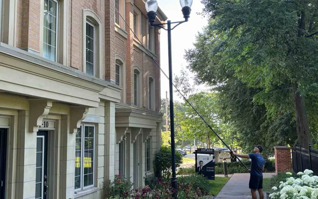 Man cleaning windows at elegant townhouse in Oakville with lush garden