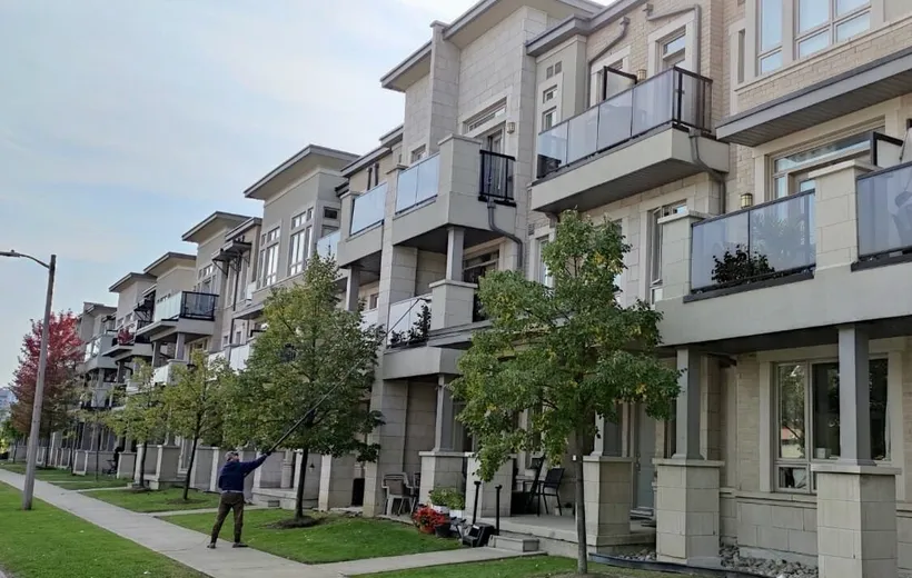 Modern urban townhouses with balconies and greenery, window cleaning