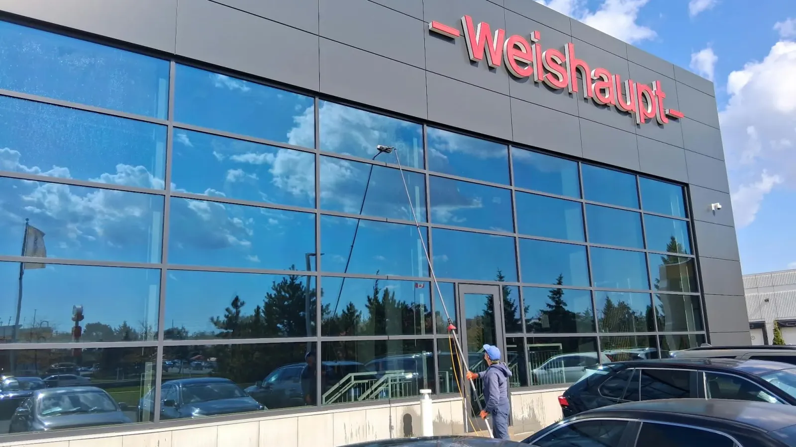 SKYPOLE technician using a water-fed pole to clean exterior windows at Weishaupt Corporation headquarters in Mississauga.