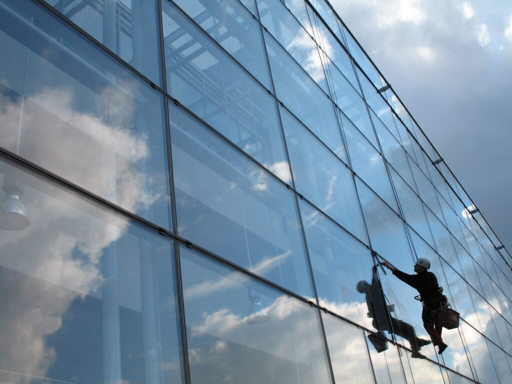 Window cleaner working on large glass facade