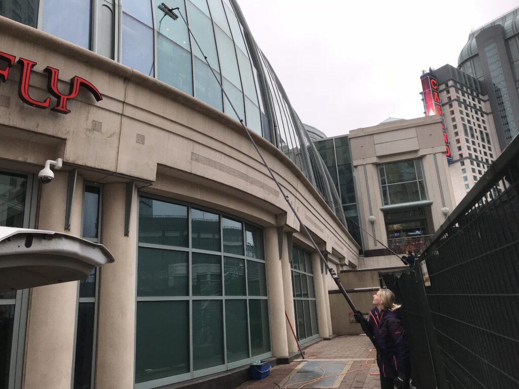 Worker cleaning building exterior with high-pressure washer