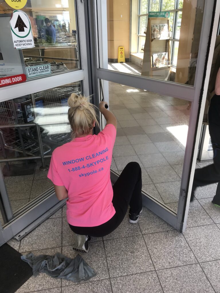 Worker in pink shirt cleaning automatic sliding door