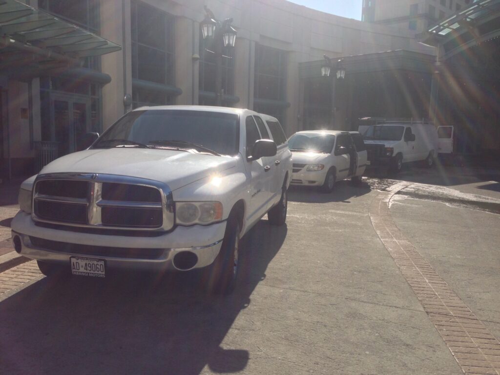 Sunlit parking area with several white vehicles