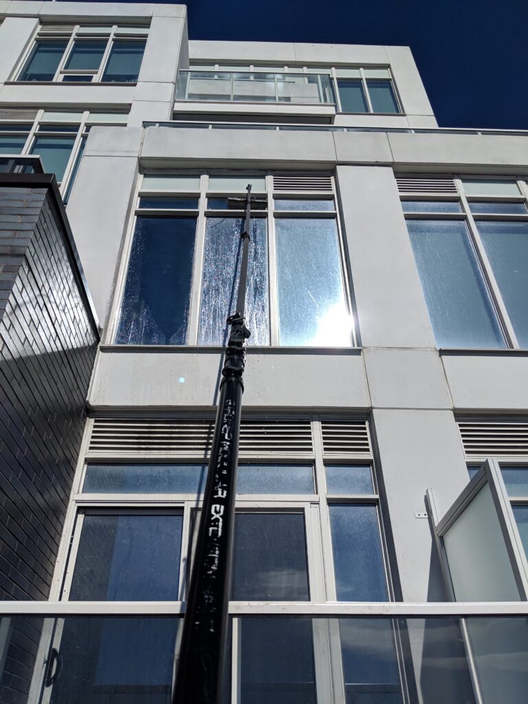 Modern building facade with pole and blue sky, cleaning window.