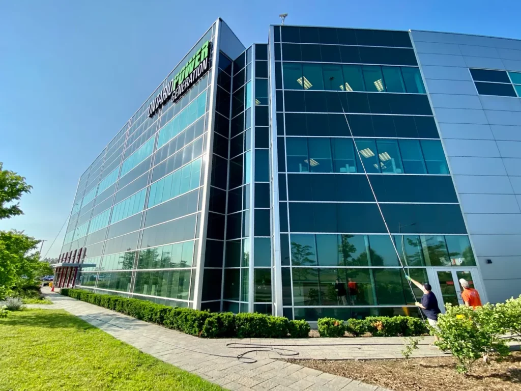 Modern office building with landscaped garden and workers outside.