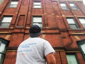 Window cleaner examining brick building exterior.