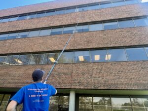 Man cleaning office windows with long pole.