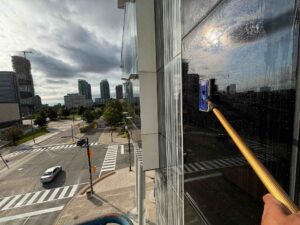 Window cleaning on high-rise building with urban backdrop