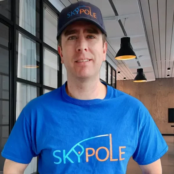Man in blue Skypole shirt smiling indoors.