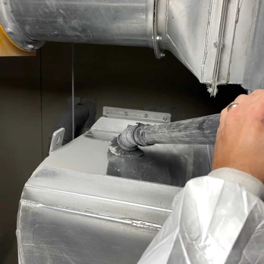 Technician applying sealant to industrial air duct.