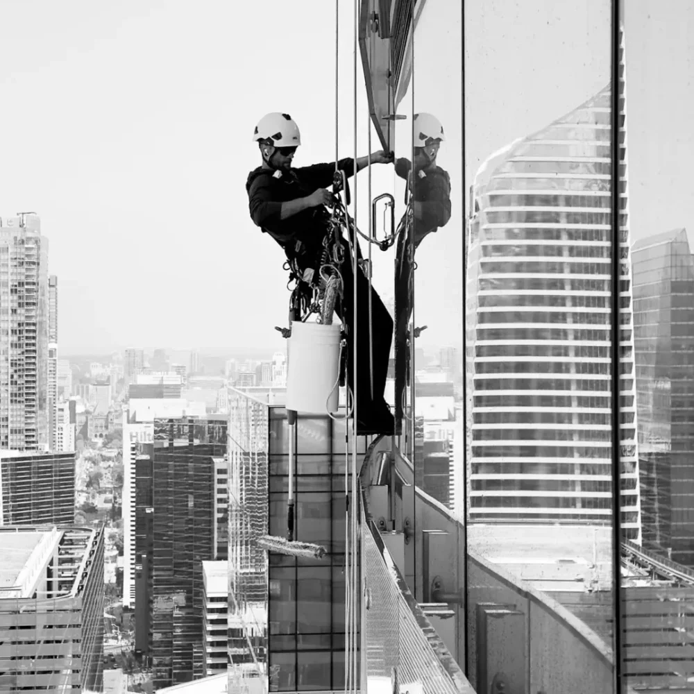 Two window washers on skyscraper exterior in black and white