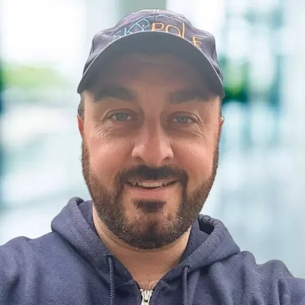 Man in cap smiling outdoors.