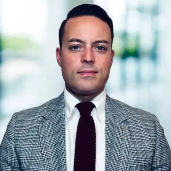 Professional man in suit and tie, blurred office background.
