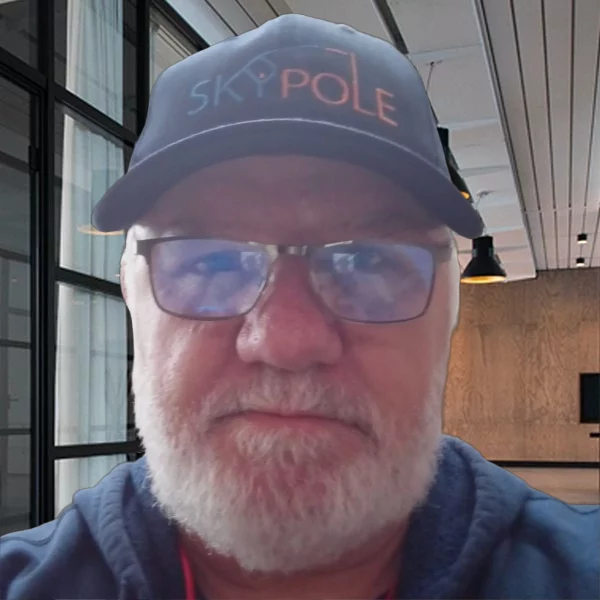 Elderly man wearing a "SKY POLE" hat indoors.