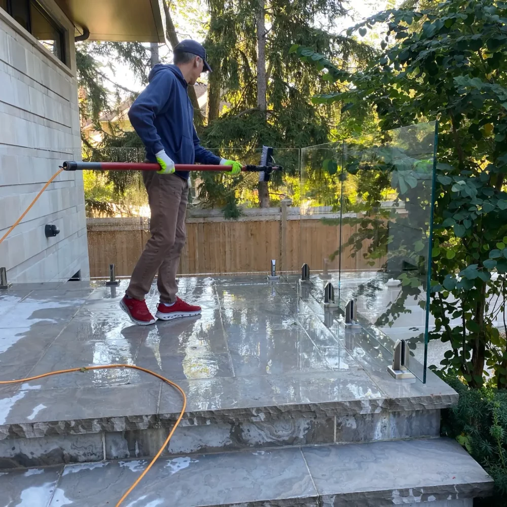 Man cleaning outdoor patio with pressure washer.