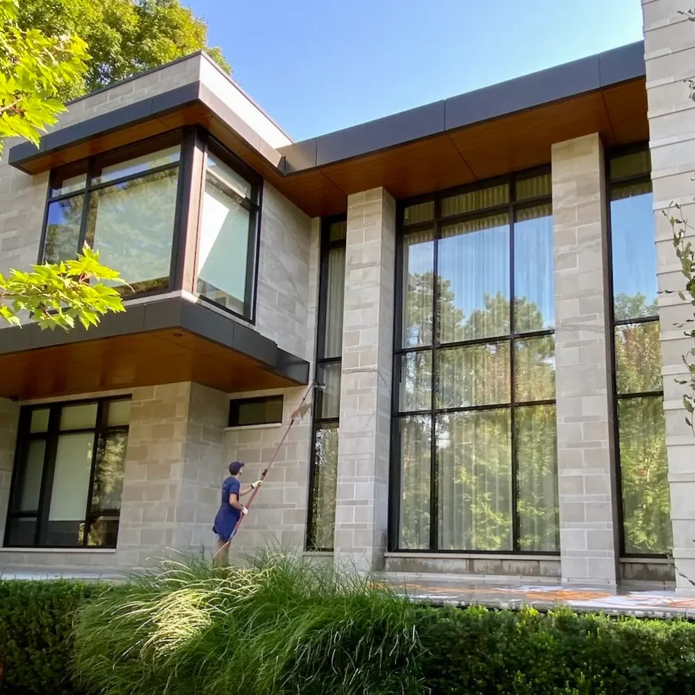 Modern house with large windows and person cleaning.
