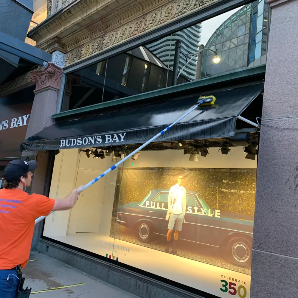 Worker cleaning Hudson's Bay store window display.